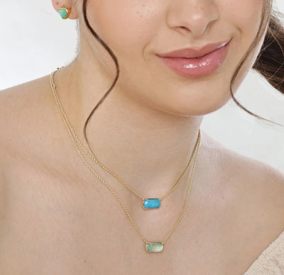 Turquoise pendant necklace featuring a custom-cut gemstone in a gold-plated setting, suspended from an elegant adjustable pendant necklace.