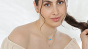 Woman wearing matching sea-blue gemstone earrings and layered necklaces with ocean-inspired stones, perfect for a beach wedding outfit.