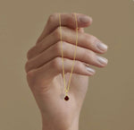 January birthstone necklace with radiant red garnet pendant, hand-set in gold-plated brass and suspended from an adjustable chain.
