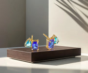 Toi et Moi stud earrings featuring emerald-cut and pear-cut gemstones with 18K yellow gold plating and push-back closure.