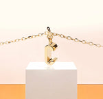 Petite Glow necklace with gold-plated C initial pendant, catching the light on a delicate anchor chain with 2-inch adjustability and lobster clasp.
