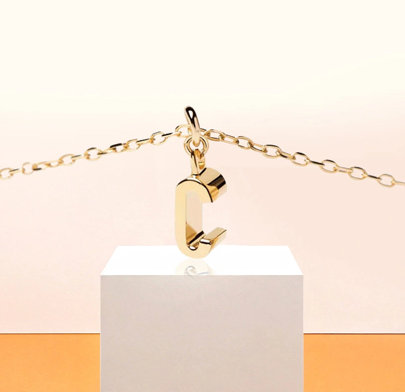 Petite Glow necklace with gold-plated C initial pendant, catching the light on a delicate anchor chain with 2-inch adjustability and lobster clasp.
