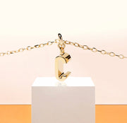 Petite Glow necklace with gold-plated C initial pendant, catching the light on a delicate anchor chain with 2-inch adjustability and lobster clasp.