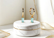 Gold hoops earrings featuring ocean-inspired blue topaz stones