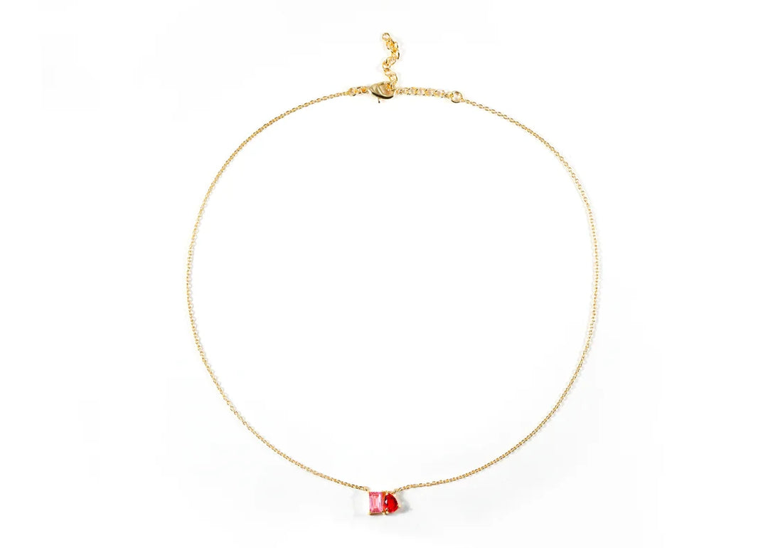 Flat lay of tourmaline and ruby two-stone gold necklace