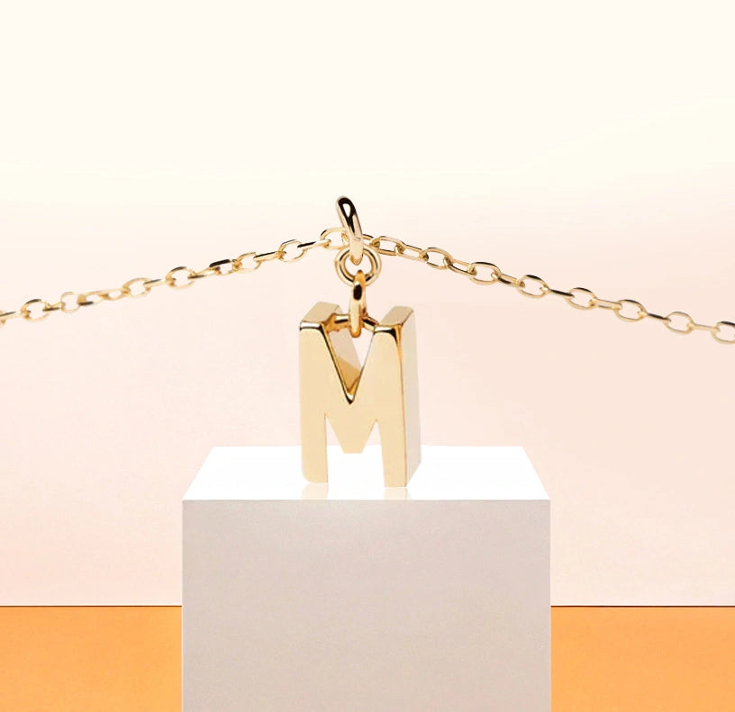 Minimalist initial M necklace in gold, a lightweight and personal accessory set on a fine anchor chain for effortless daily sophistication.
