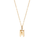 Petite gold initial M pendant hanging from an anchor chain, designed for subtle shimmer and perfect for layering with other delicate pieces.