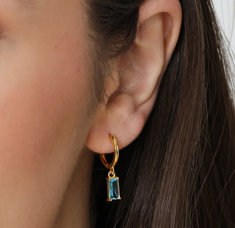 Blue topaz hoop earrings for December birthstone, set in gold with a radiant shine.