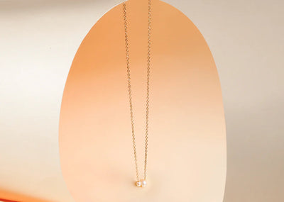 A pearl charm necklace featuring a delicate chain with two lustrous pearl charm, adding a classic and elegant touch to any outfit.
