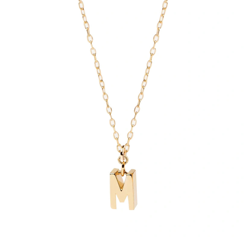 Petite gold initial M pendant hanging from an anchor chain, designed for subtle shimmer and perfect for layering with other delicate pieces.