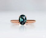 Teal sapphire engagement ring with elegant oval gemstone and diamond accents in gold setting

