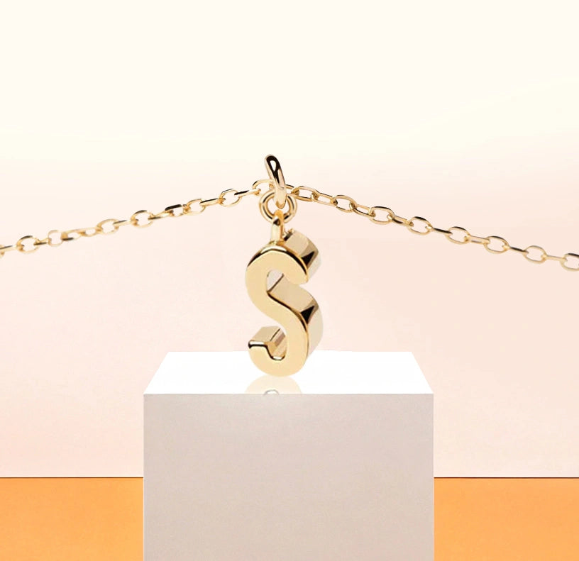 Delicate gold necklace with letter S pendant, glowing subtly on a fine adjustable anchor chain, perfect for a personalized minimalist look.