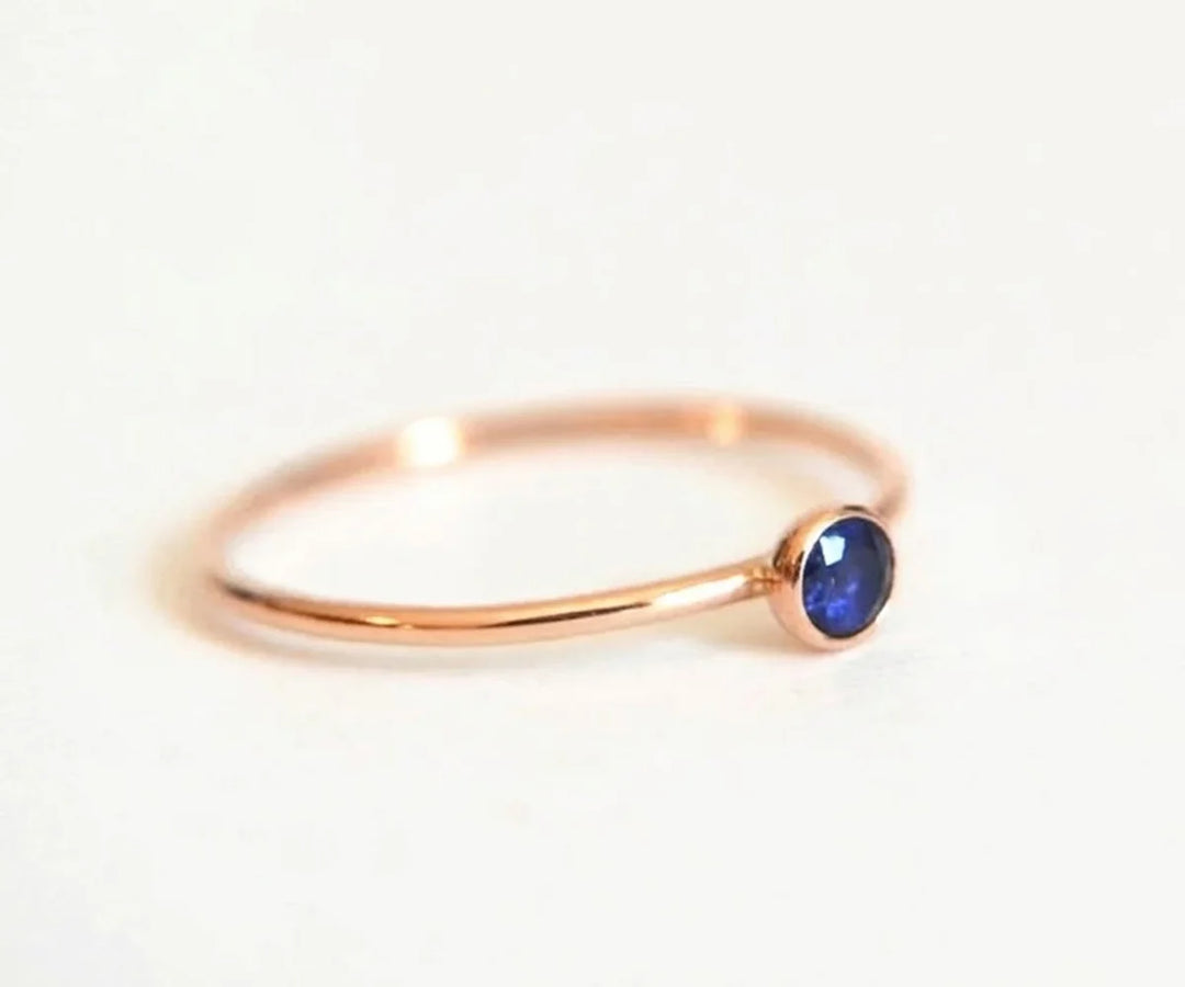 Minimalist blue sapphire engagement ring with solitaire gemstone on a delicate gold band