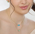 Turquoise pendant necklace featuring a custom-cut gemstone in a gold-plated setting, suspended from an elegant adjustable pendant necklace.
